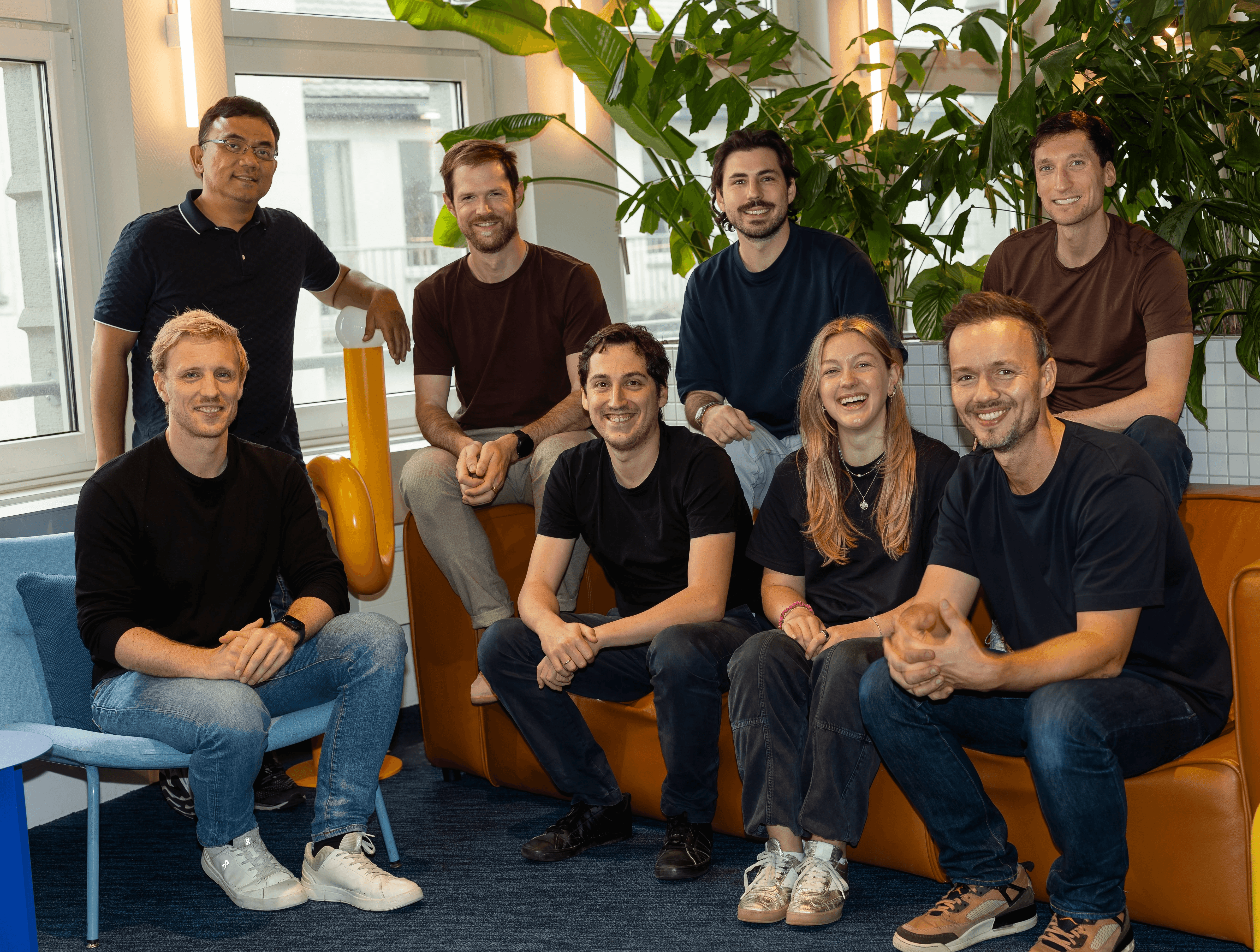 Group of eight Ahead Health team members posing together on an orange office sofa